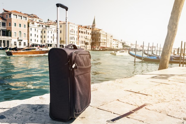 small-suitcase-on-travel-urban-background-venice-italy-horizontal-toning-travel-vacation-concept_1220-1302