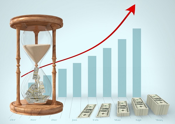 Currency flowing through hour glass and stack of dollar bills against graph bar in background